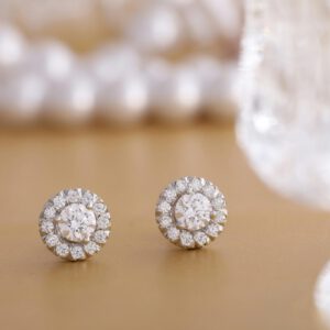 Close-up of round diamond earrings on a gold background, showcasing luxury and elegance.