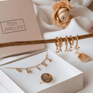 Stylish jewelry set with personalized letter charms displayed elegantly in a box.