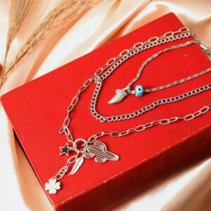 Stylish silver necklace with charms on a vibrant red book, perfect for fashion editorials.